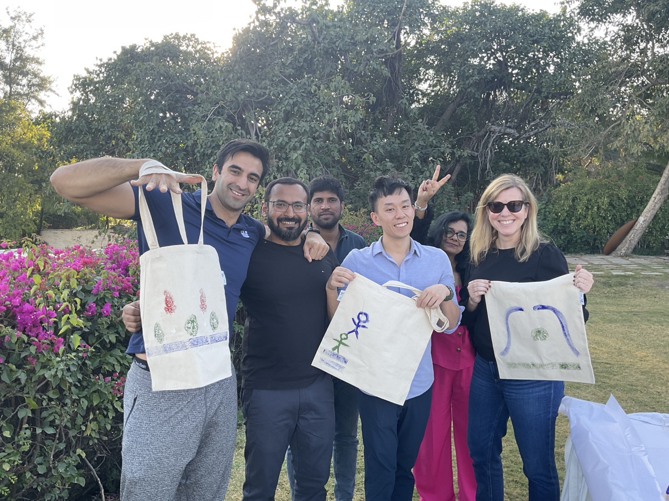 Corporate team holding block-printed tote bags at an outdoor team building activity